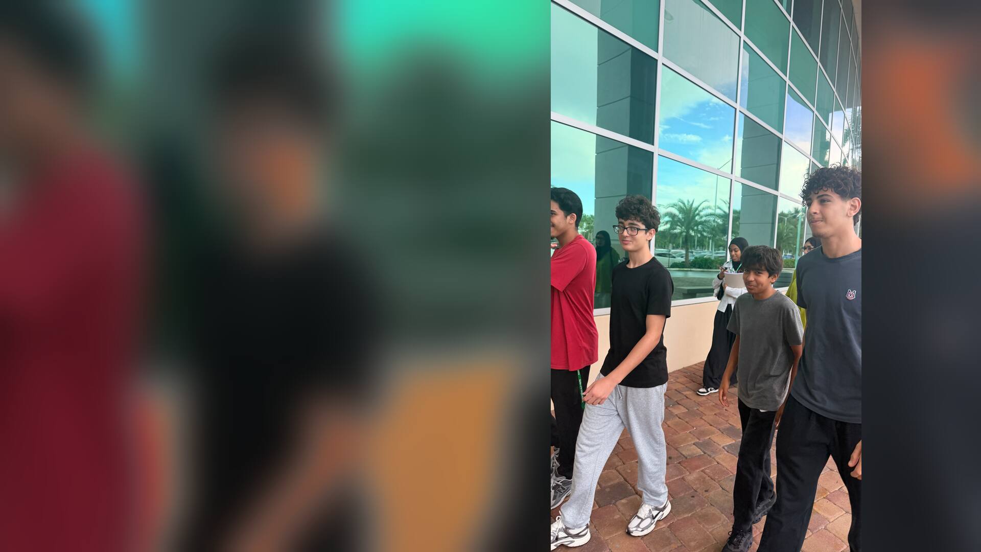 Students walking past the glass walls of a campus building