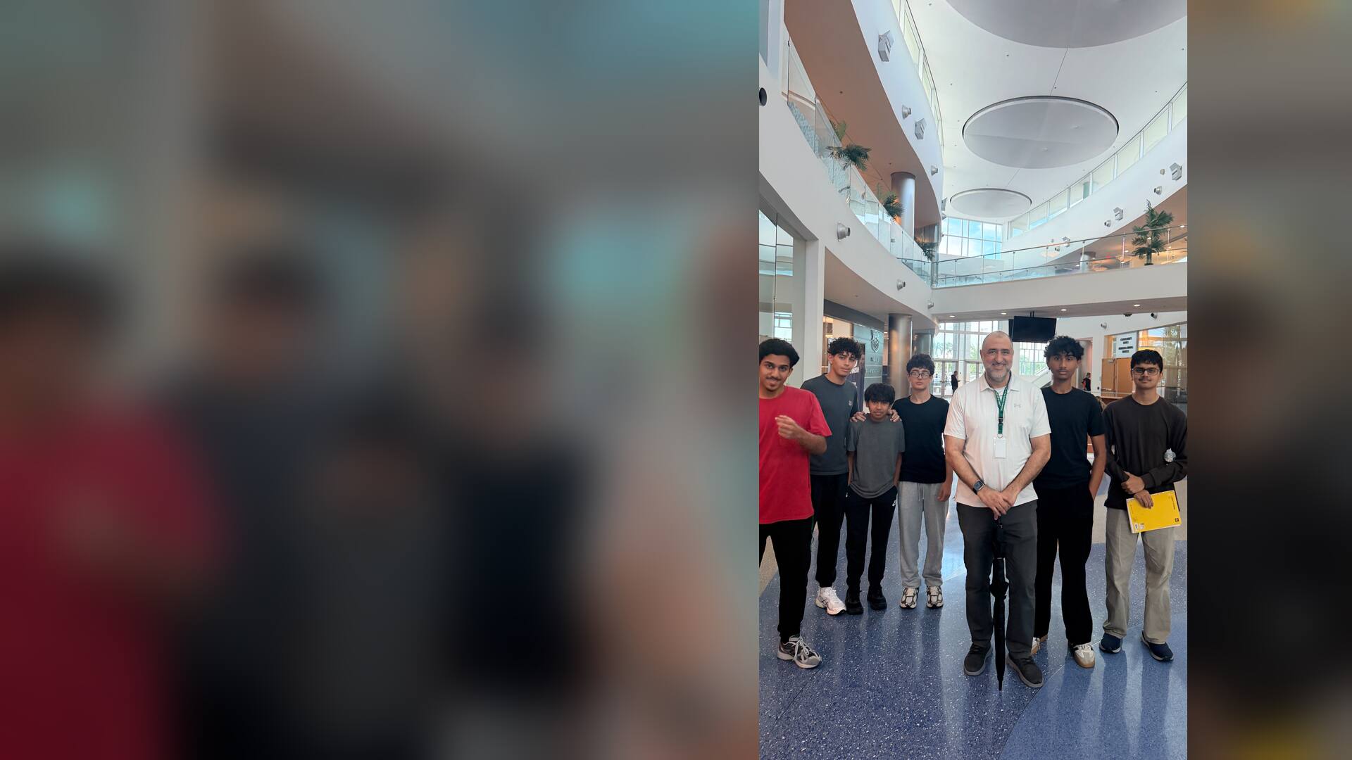 Students and a teacher posing in the open atrium