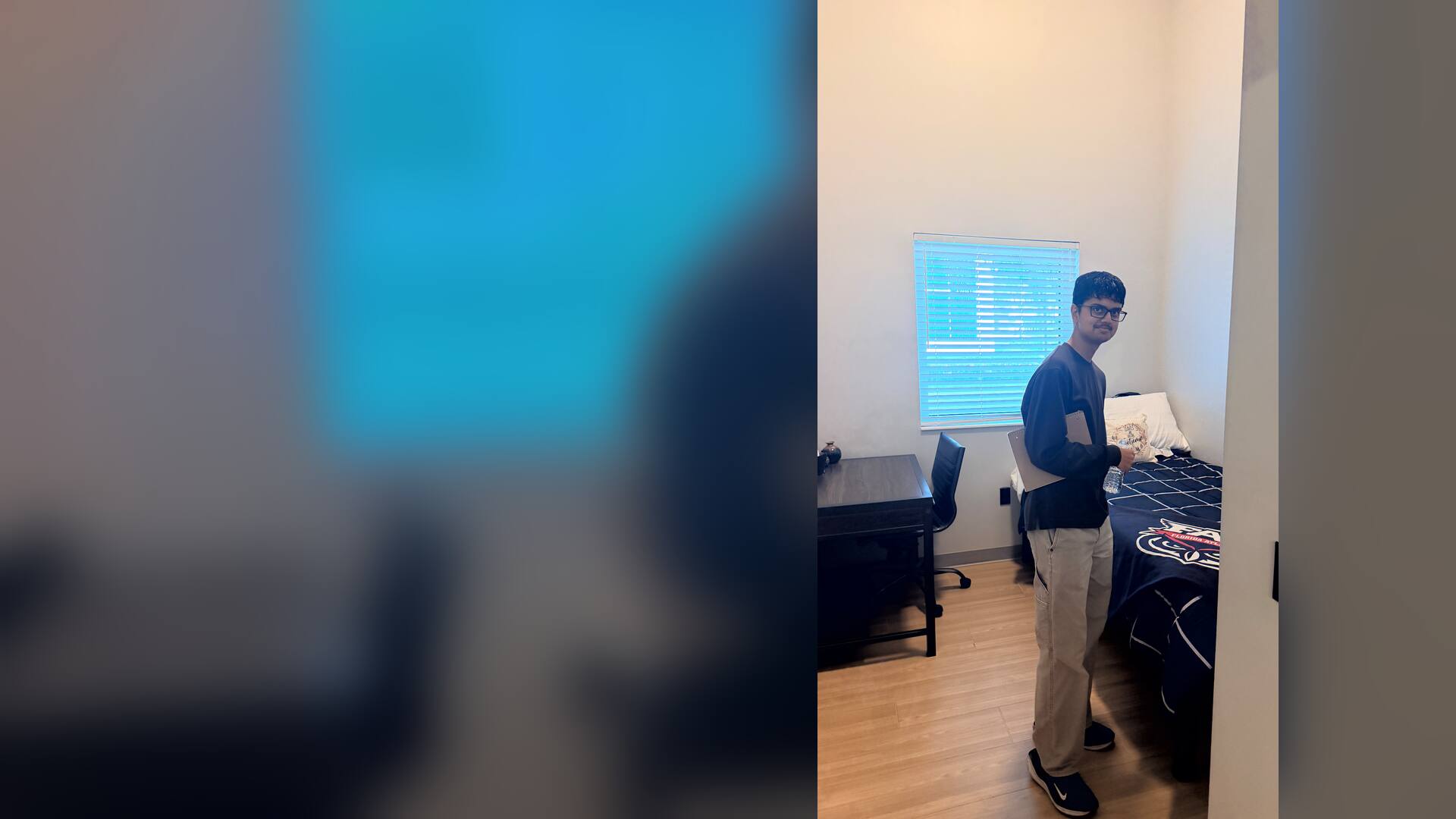 A student smiling inside a residence hall bedroom
