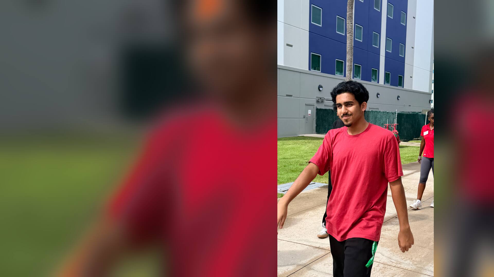 A smiling student walking outside a residence hall