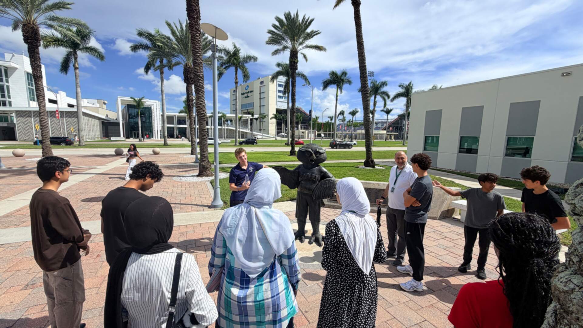 The group gathered around a guide on the palm-lined plaza