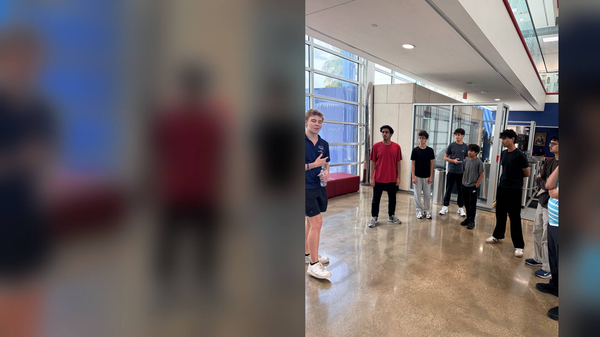 Students listening to a guide in a bright building lobby