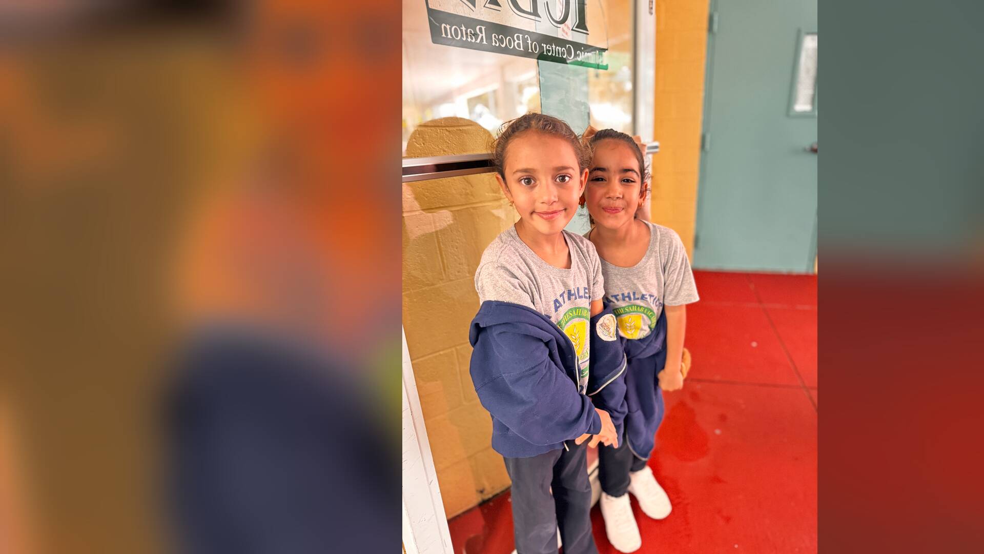Two young friends lean together for a photo by the doorway