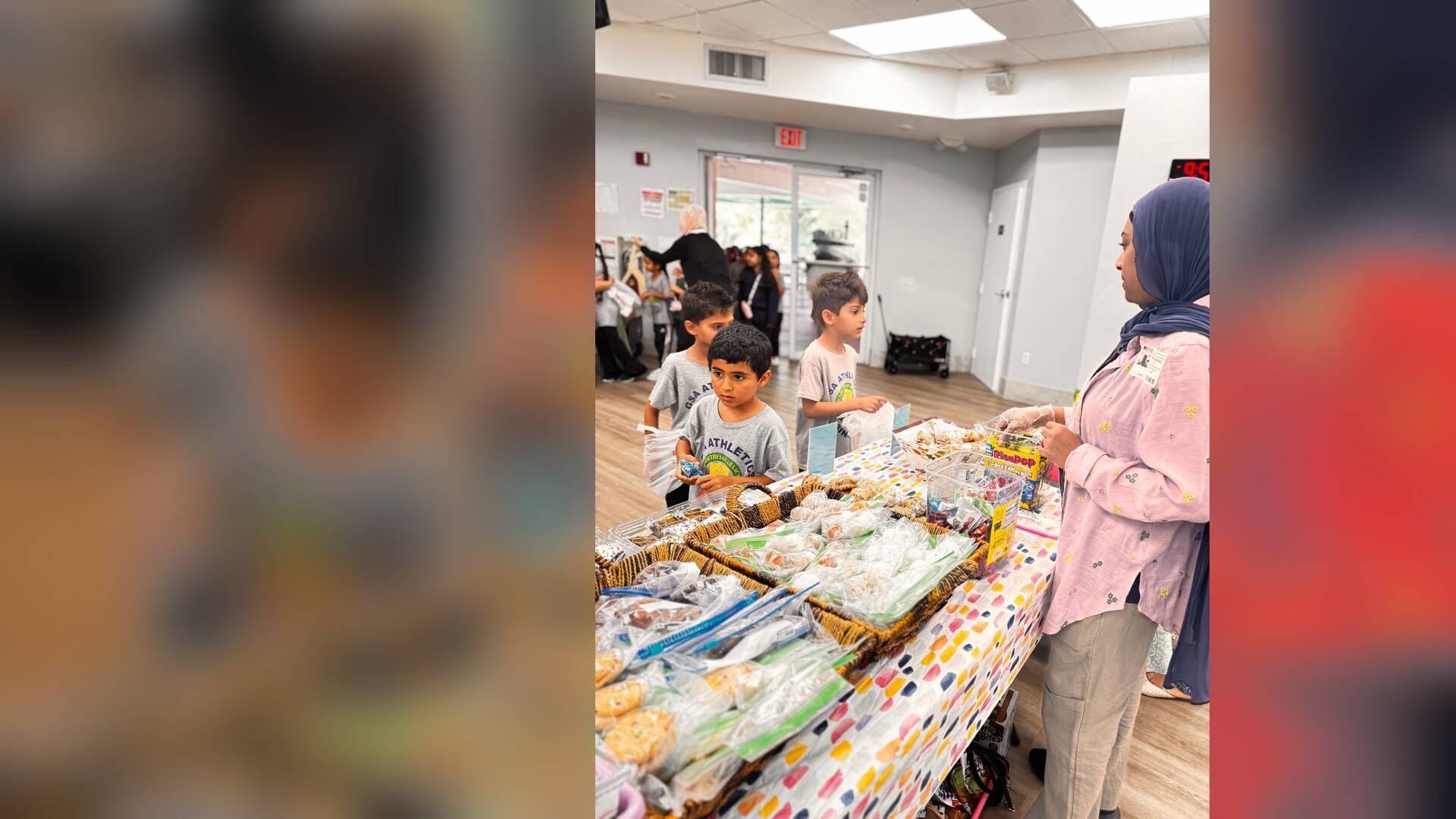 A volunteer in a pink top looks after young shoppers at the cookie table