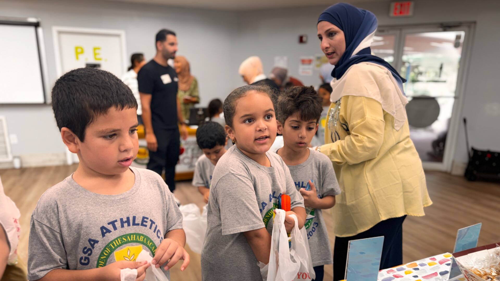 Three young shoppers hold open their bags at the cookie table