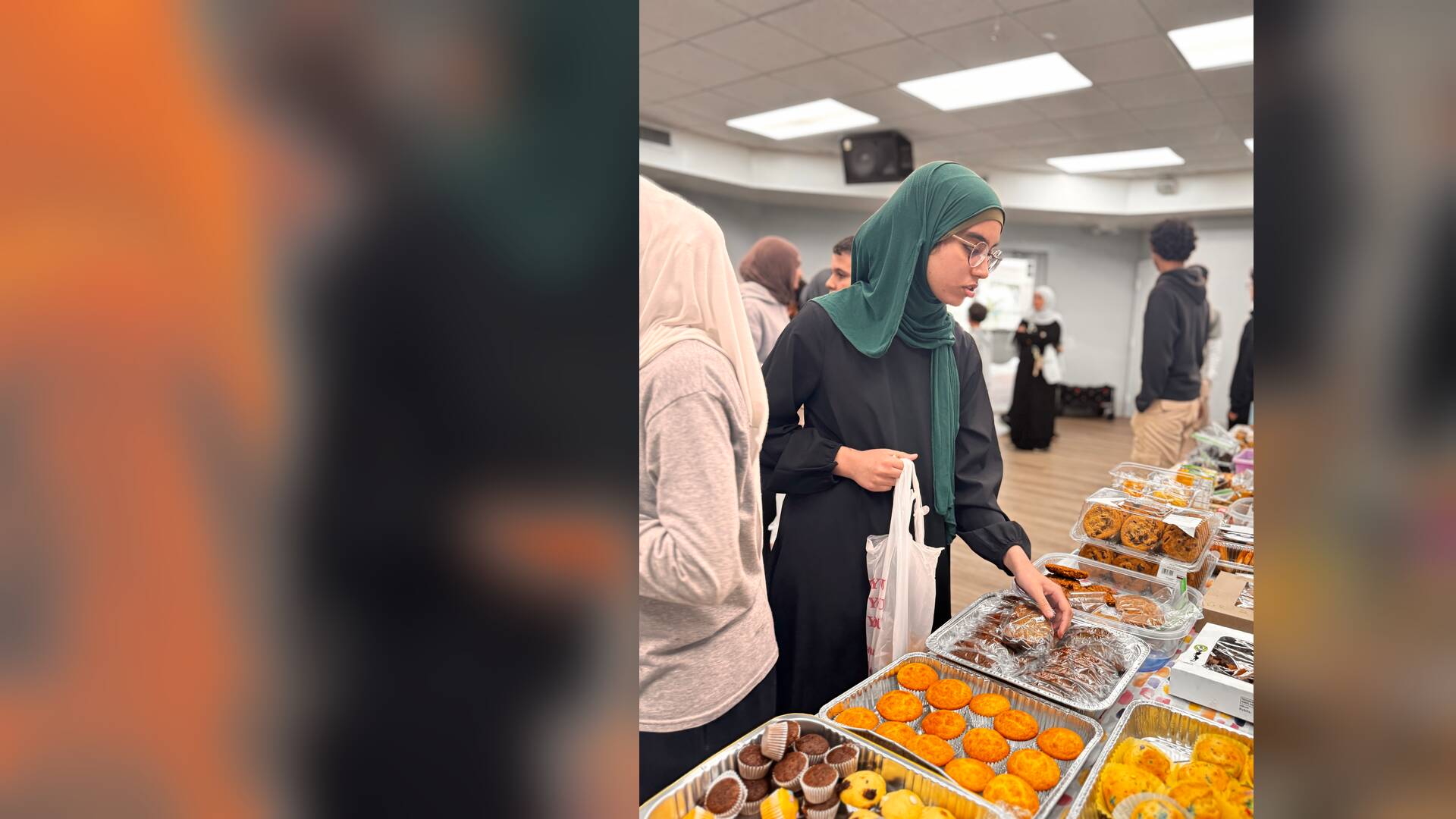A student reaches for a treat from trays of muffins and brownies