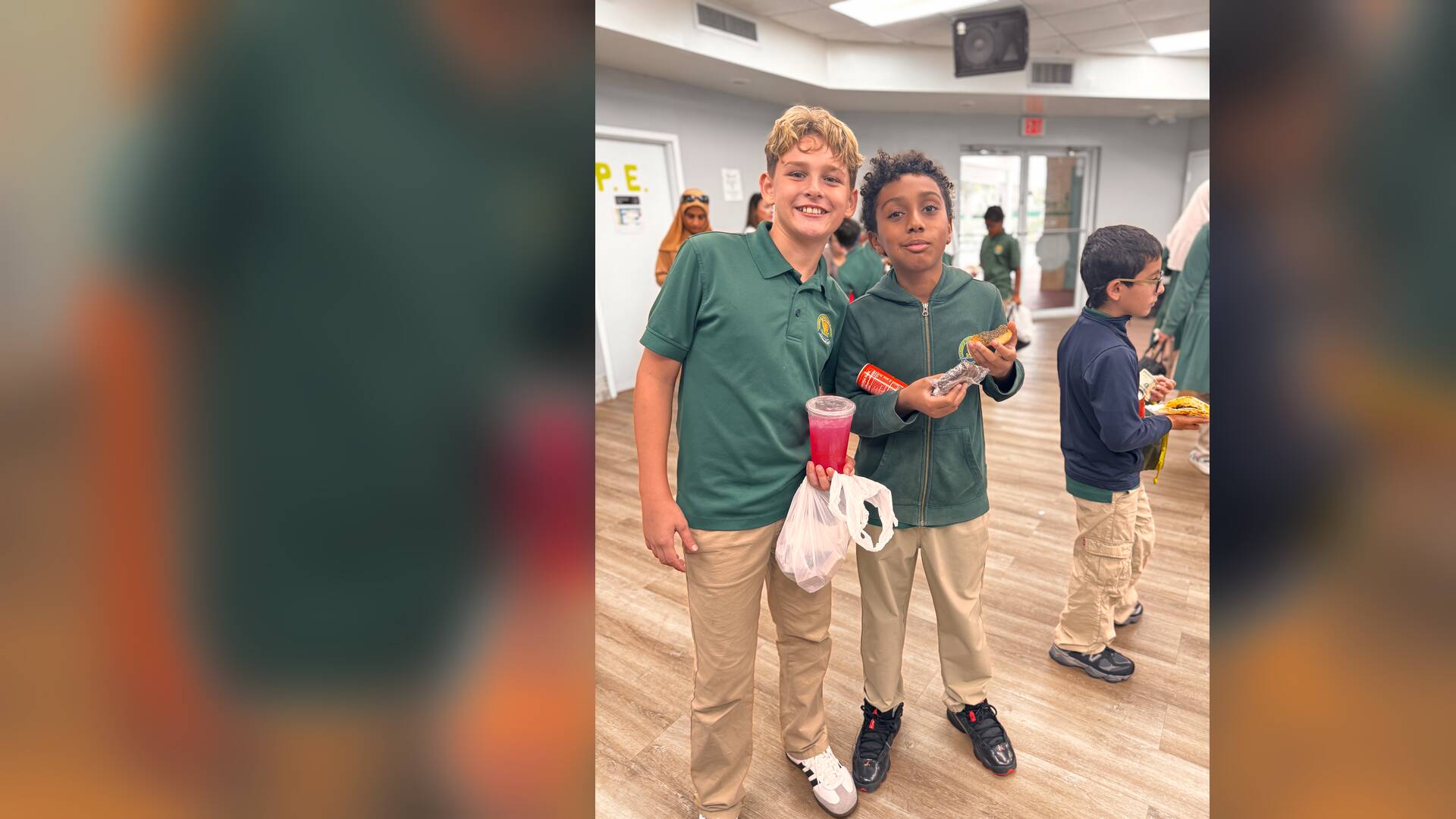 Two friends show off a pink drink and a snack from the sale