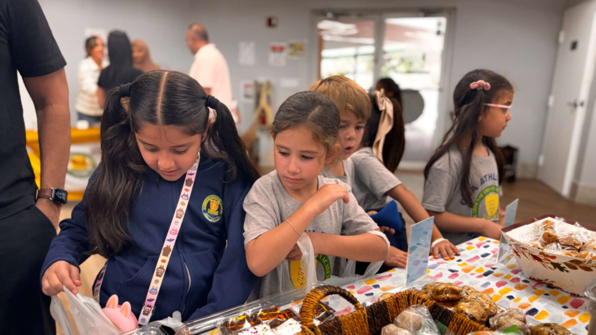 Young students lean over baskets of wrapped cookies