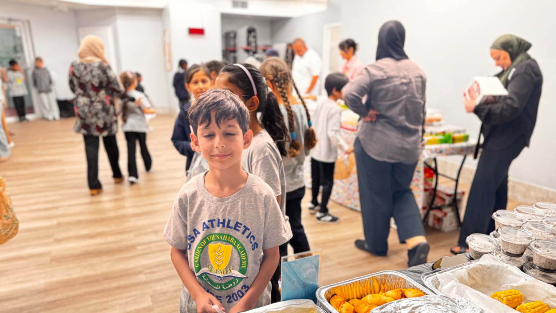 A young student stands ready at the savory table, bag in hand