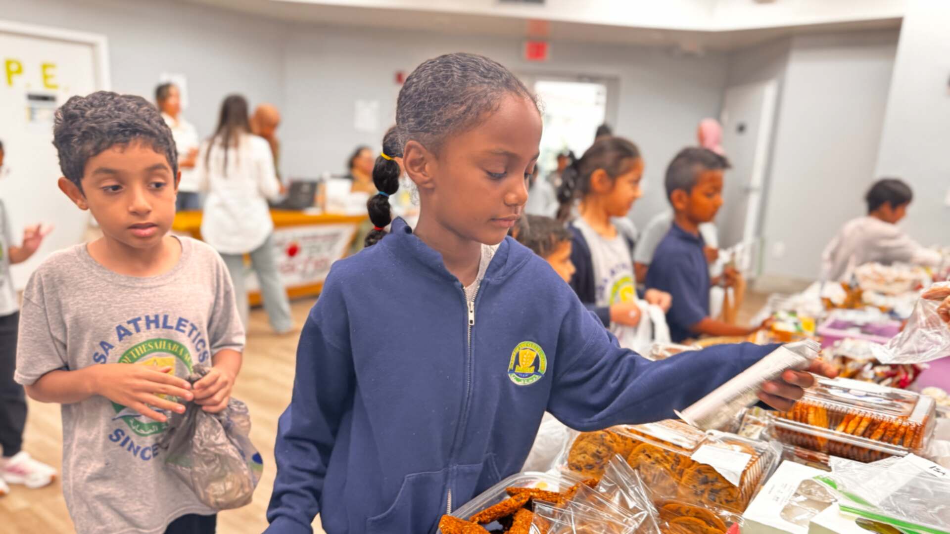 A student reaches for cookies as a classmate waits nearby