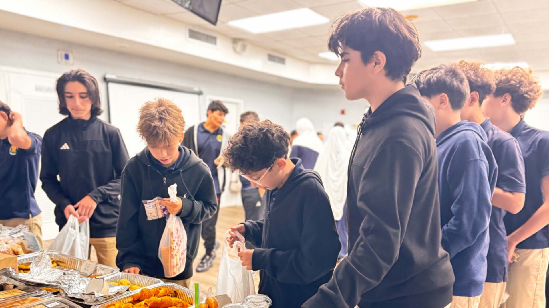Older students gather around cups of pudding and pastries