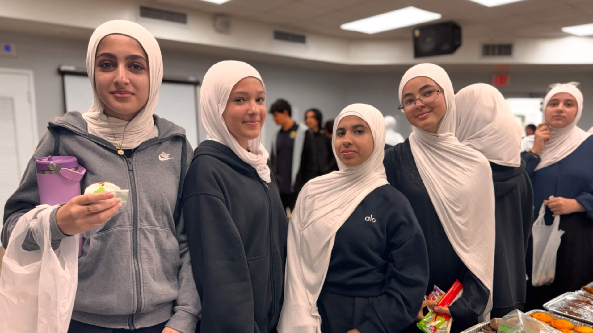 A smiling group of older students lines up with a cupcake and snacks