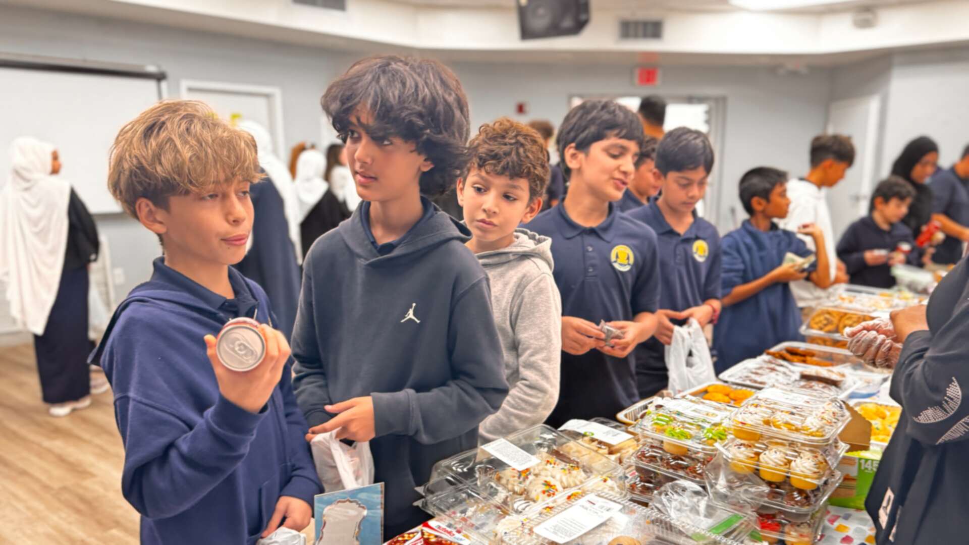 An older student holds up a mini jar while classmates browse
