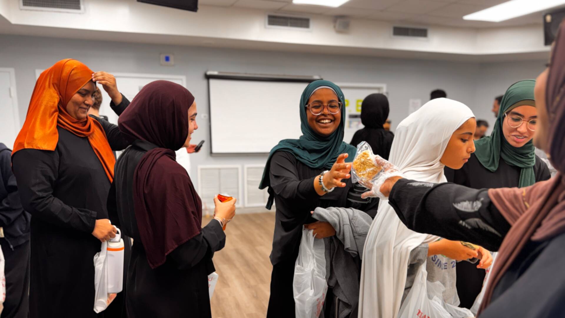 Older students share a laugh as treats are handed across the table