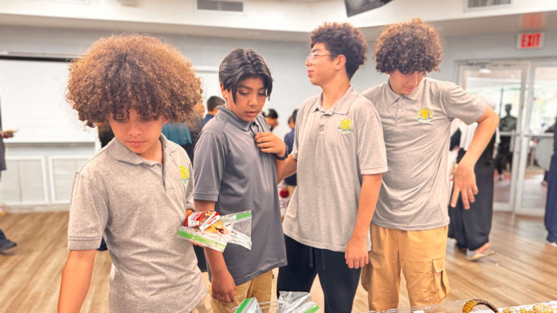 Students in grey polos sort through bags of snacks
