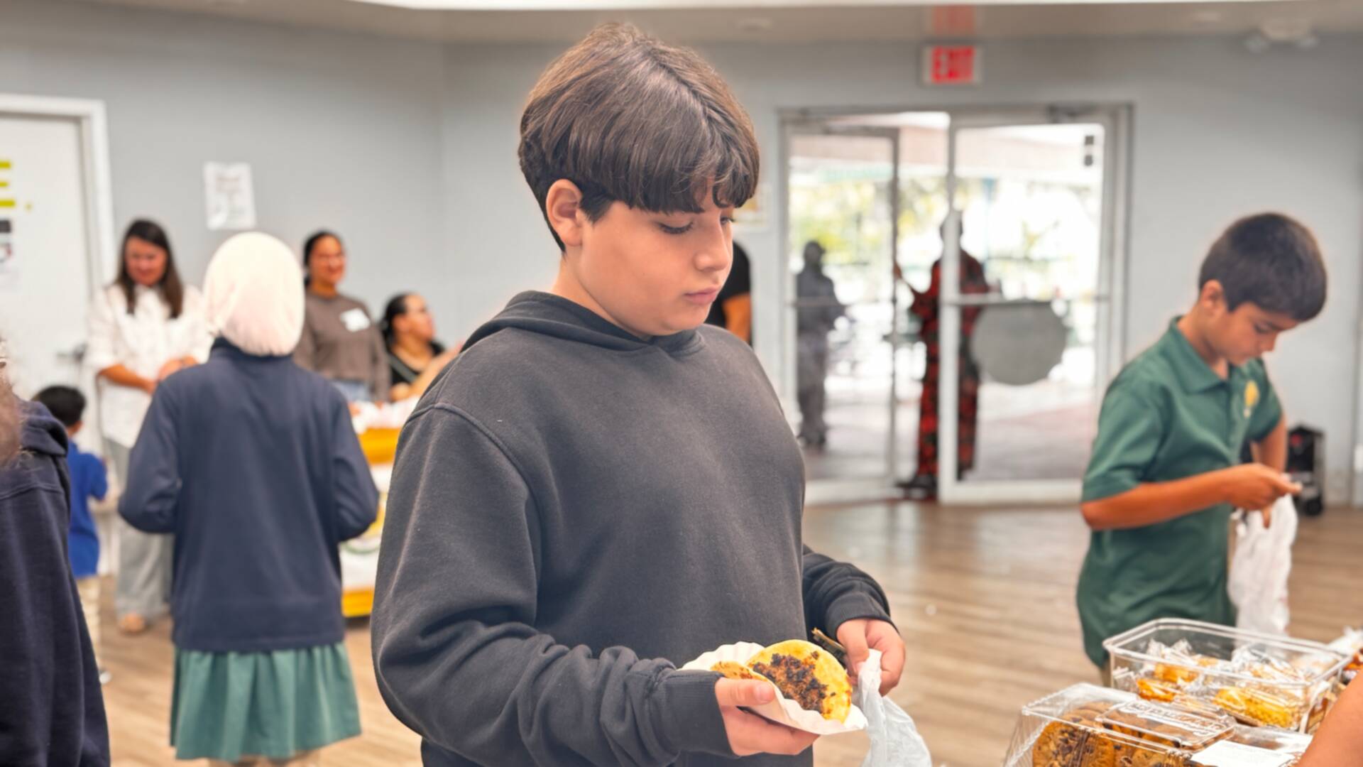 A student carefully carries a fresh cookie on a napkin