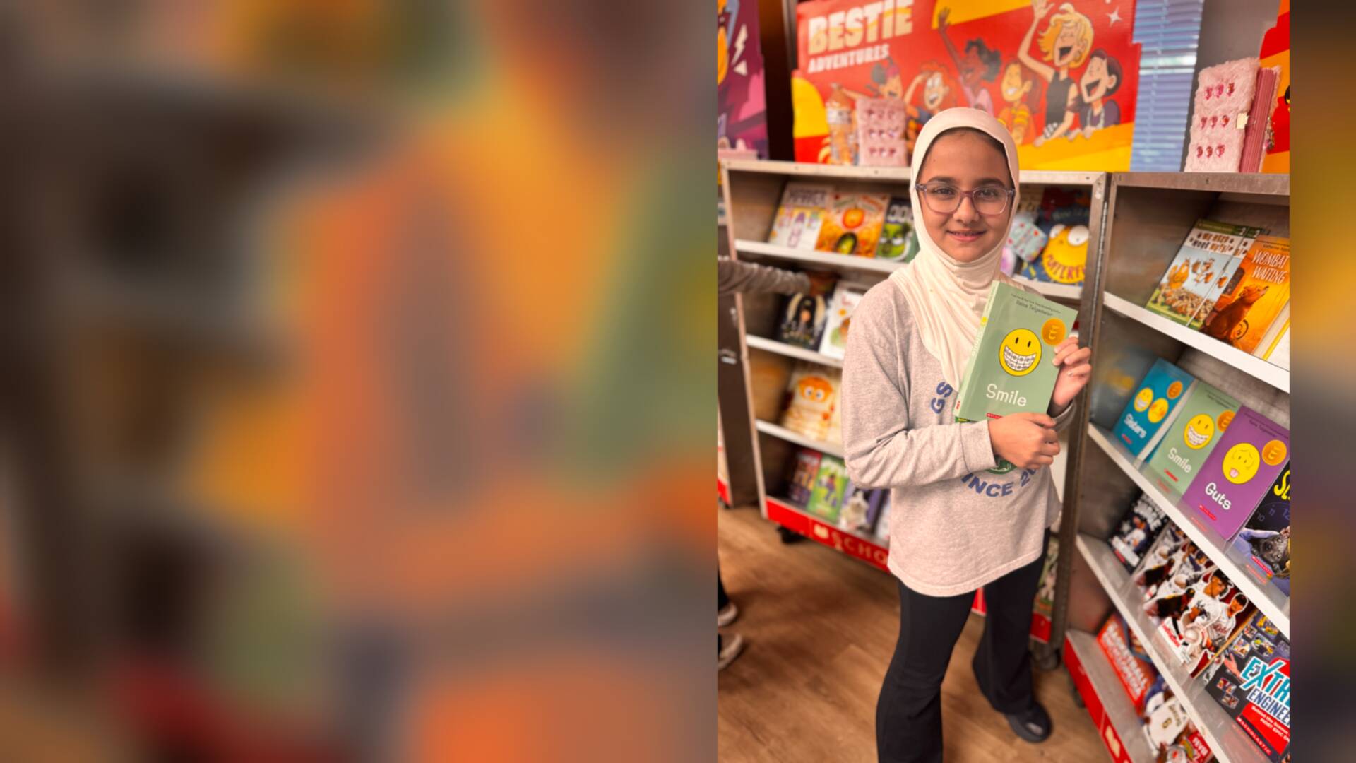 A student holding a graphic novel beside the bookshelves