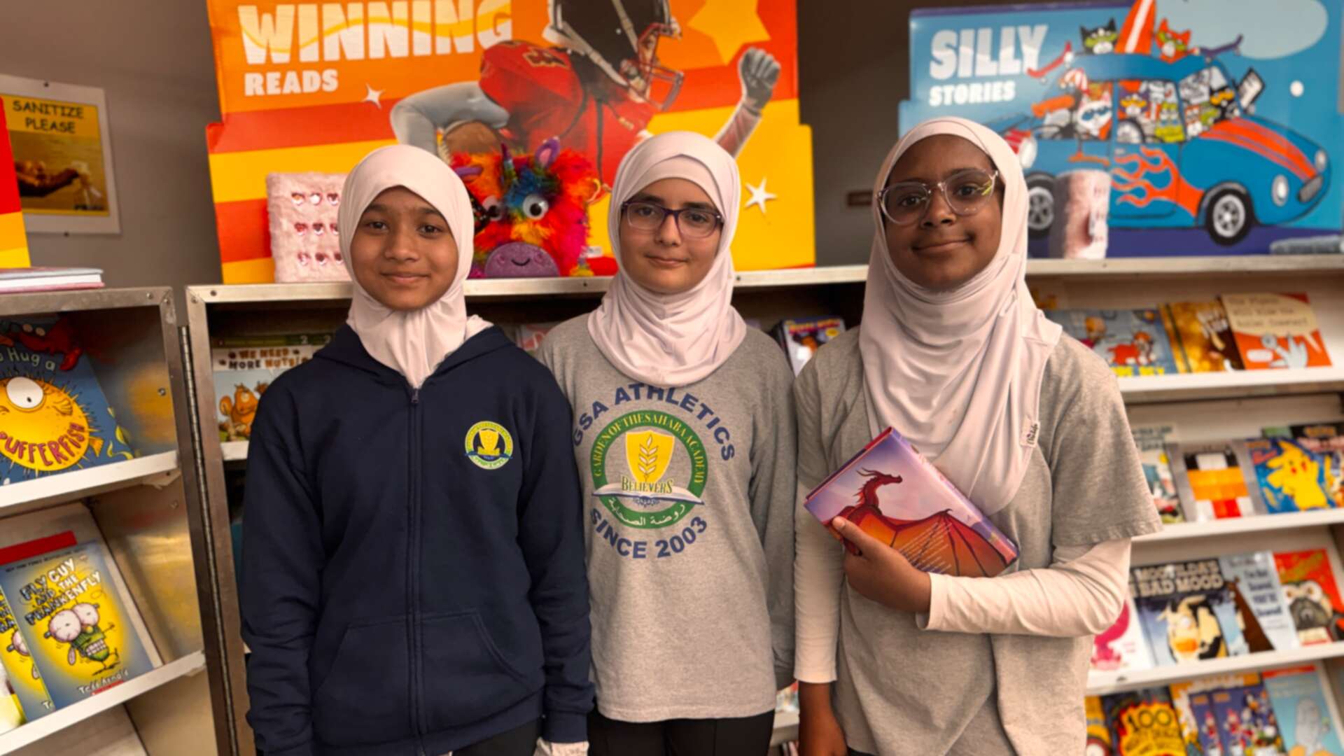 Three students posing among the book displays