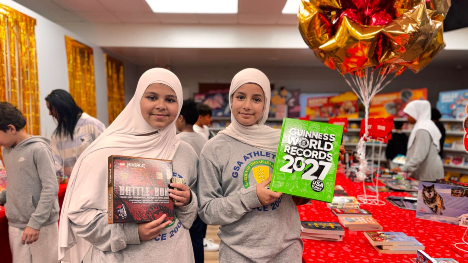 Two students holding up a records book and a building book