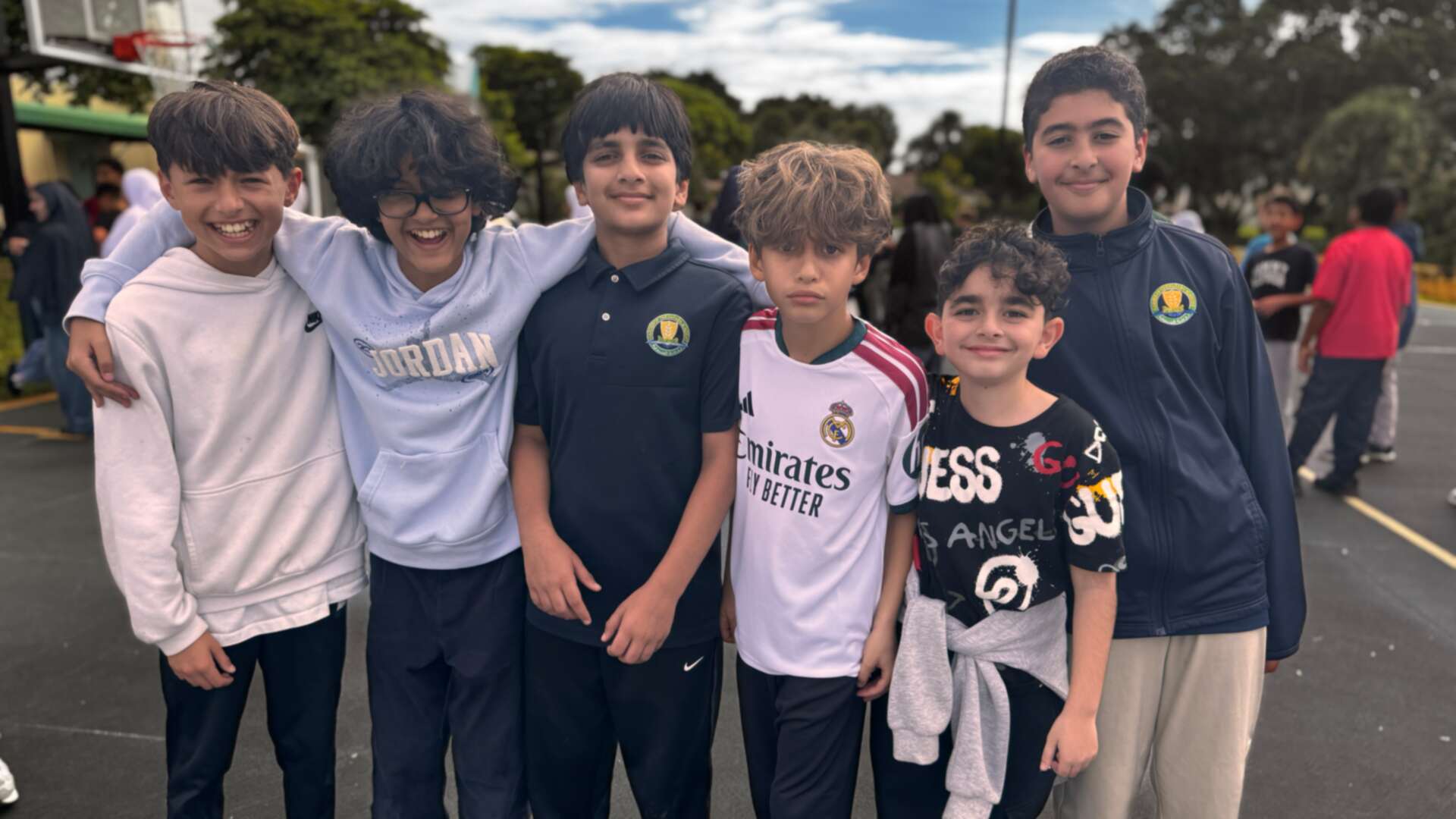 A row of grinning buddies in hoodies and jerseys on the basketball court