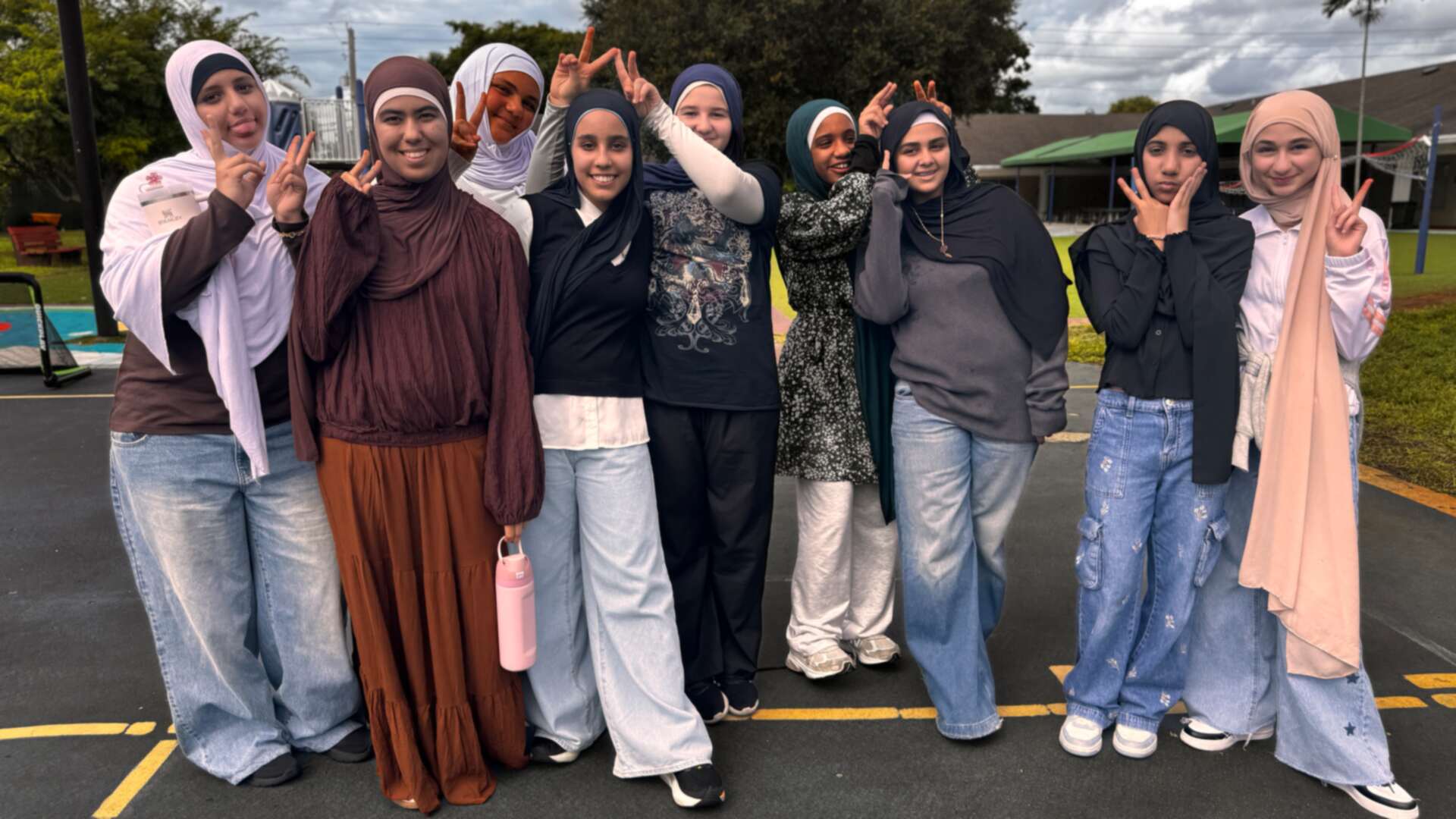 A cheerful crowd of friends in browns, creams and denim strike playful poses