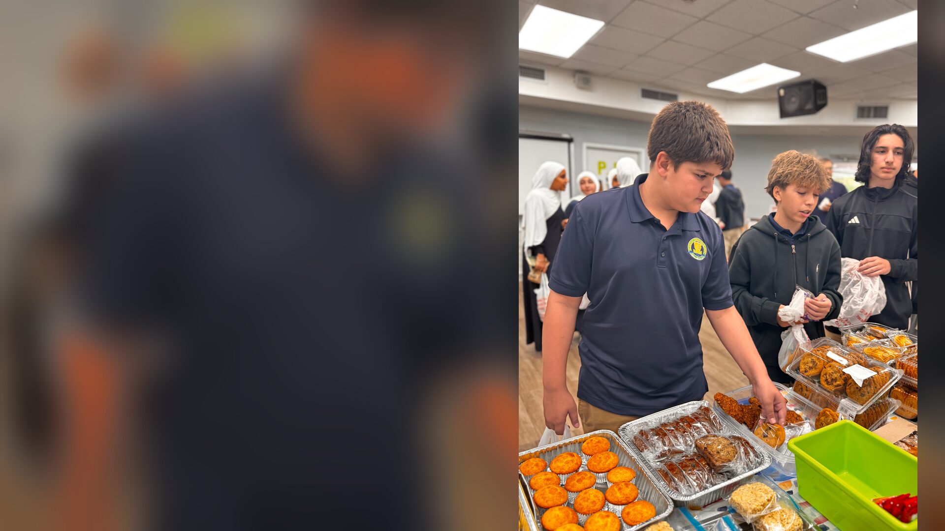 Students pick out cookies and muffins from trays at the bake sale table.