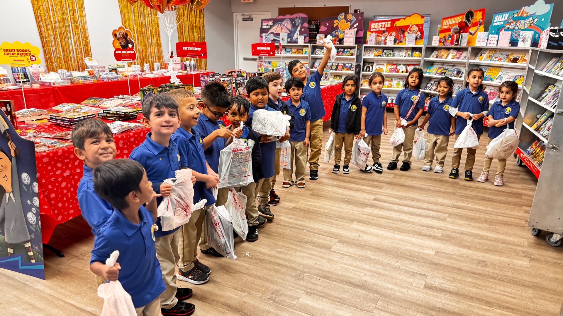 Young students in navy uniforms line up holding bags at the book fair.