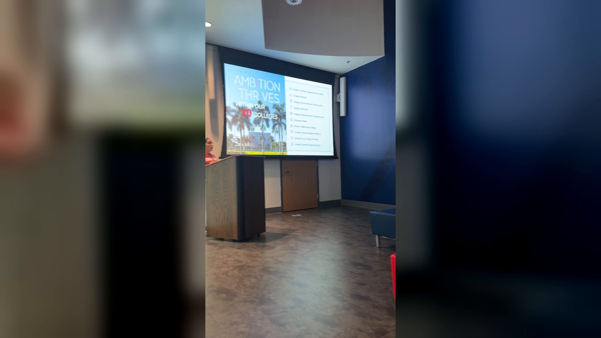 The camera pans across a lecture room at Florida Atlantic University, from a presentation screen to the glowing FLORIDA ATLANTIC wall letters above students seated on a couch.