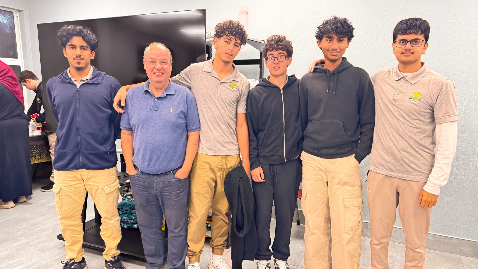 Five students and an adult stand side by side for a group photo.