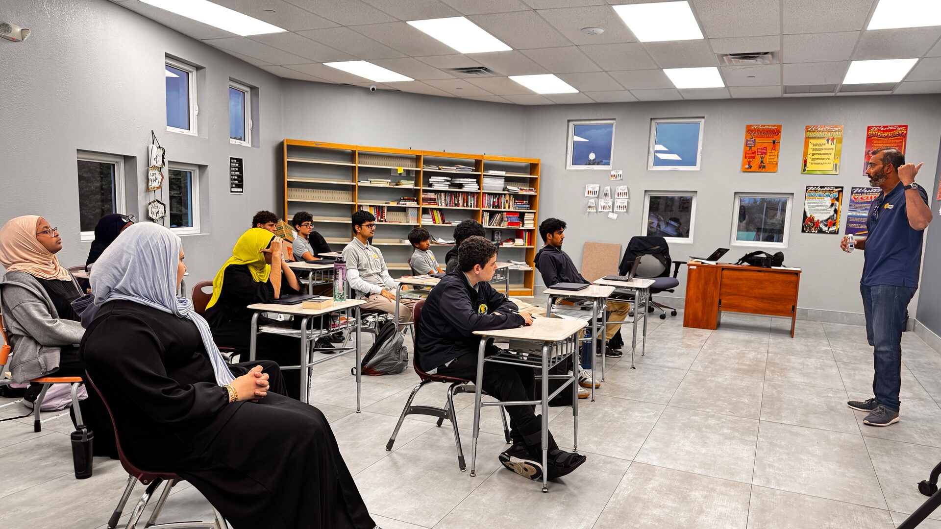 Students seated at desks listen as a guest speaker addresses the class from the front of the room.