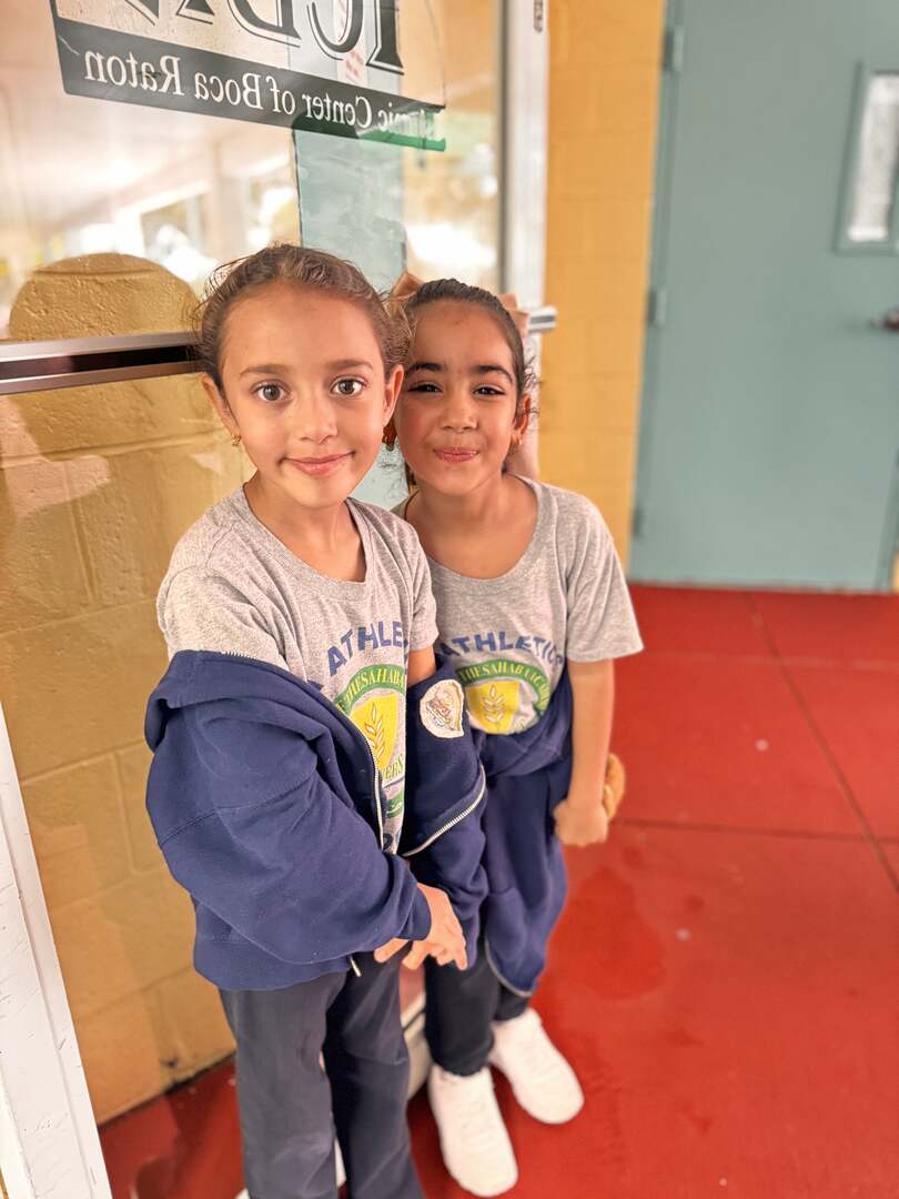 Two young friends lean together for a photo by the doorway
