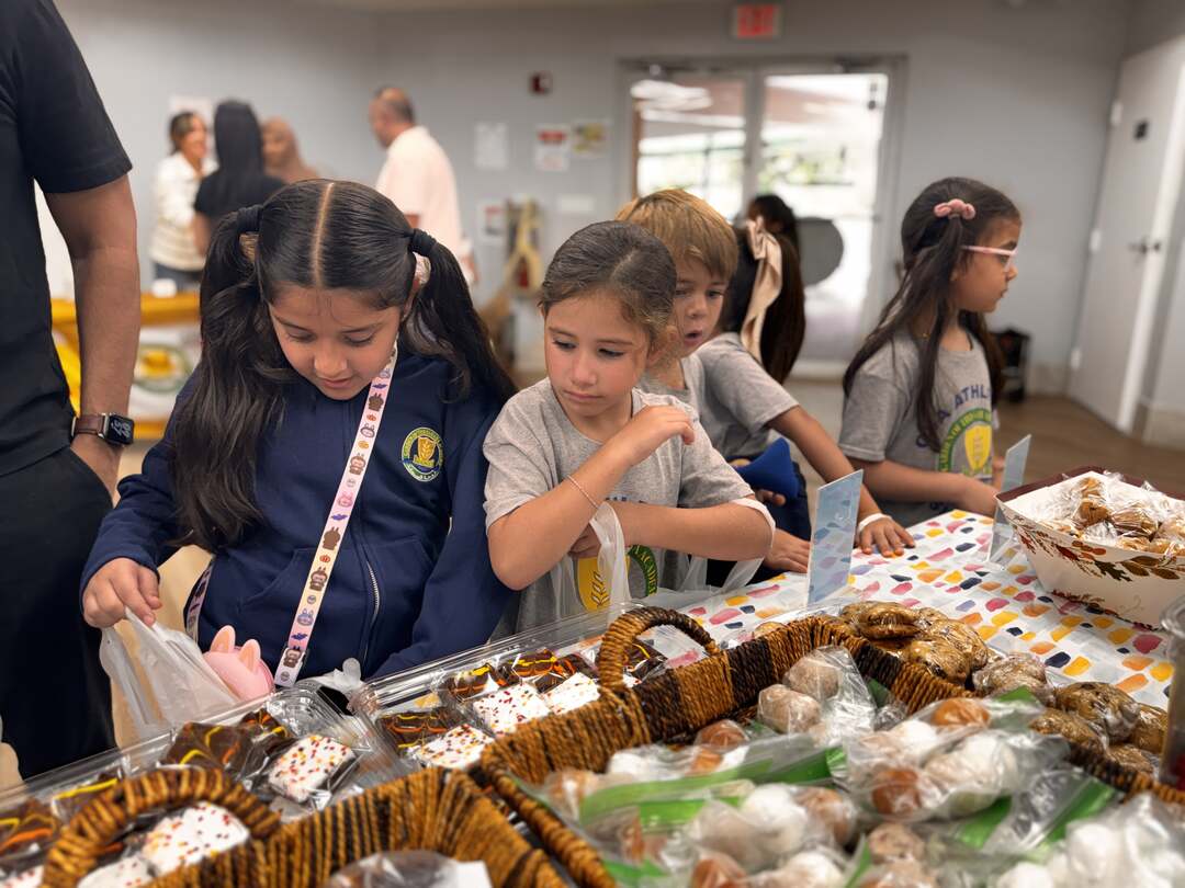 Young students lean over baskets of wrapped cookies