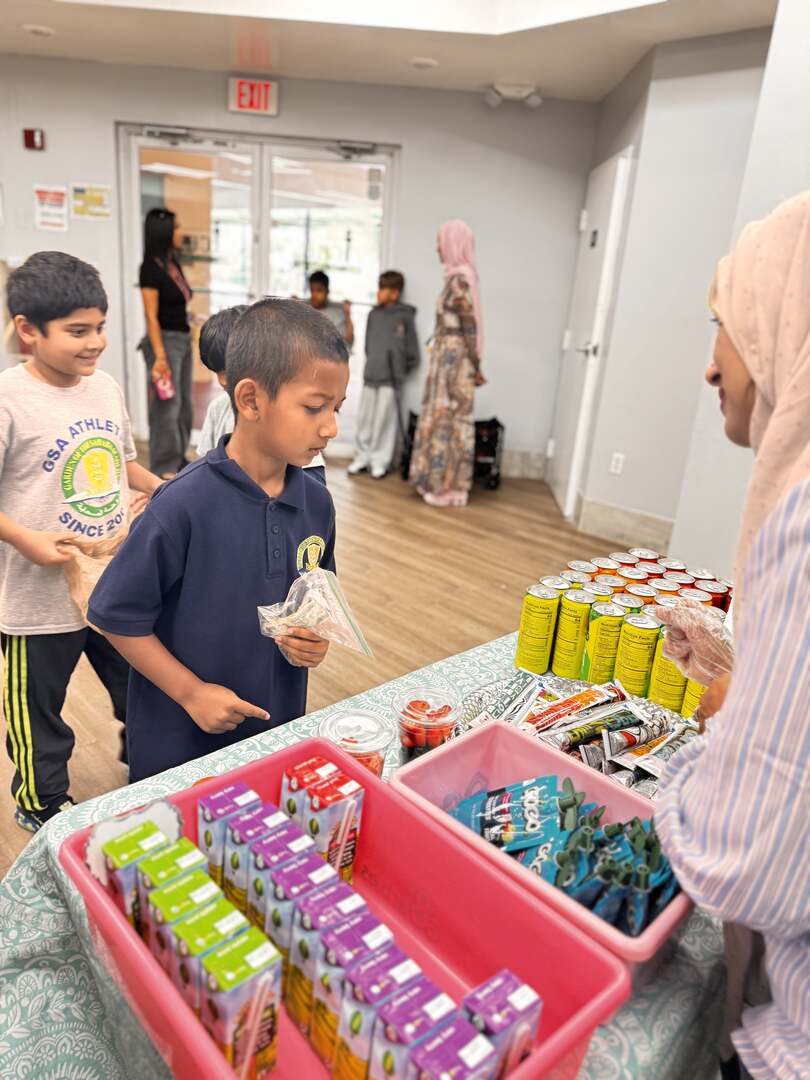 Young students pick out juice boxes and snacks at the drinks table