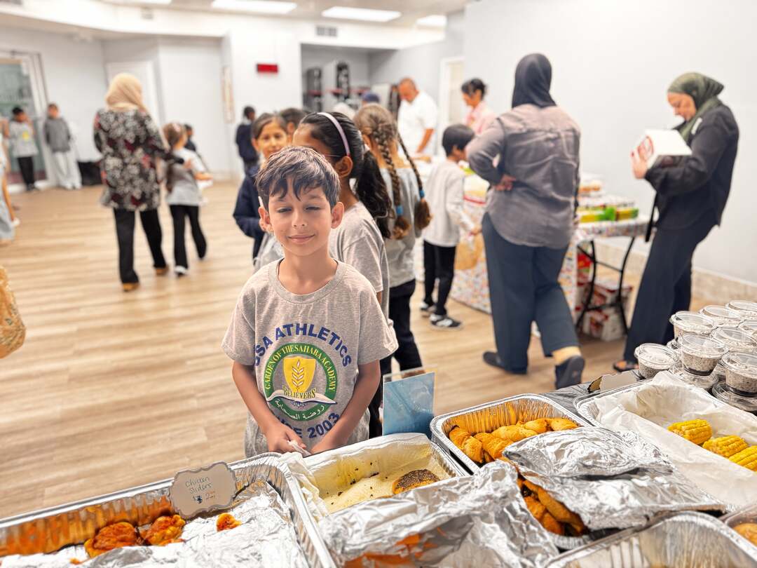 A young student stands ready at the savory table, bag in hand