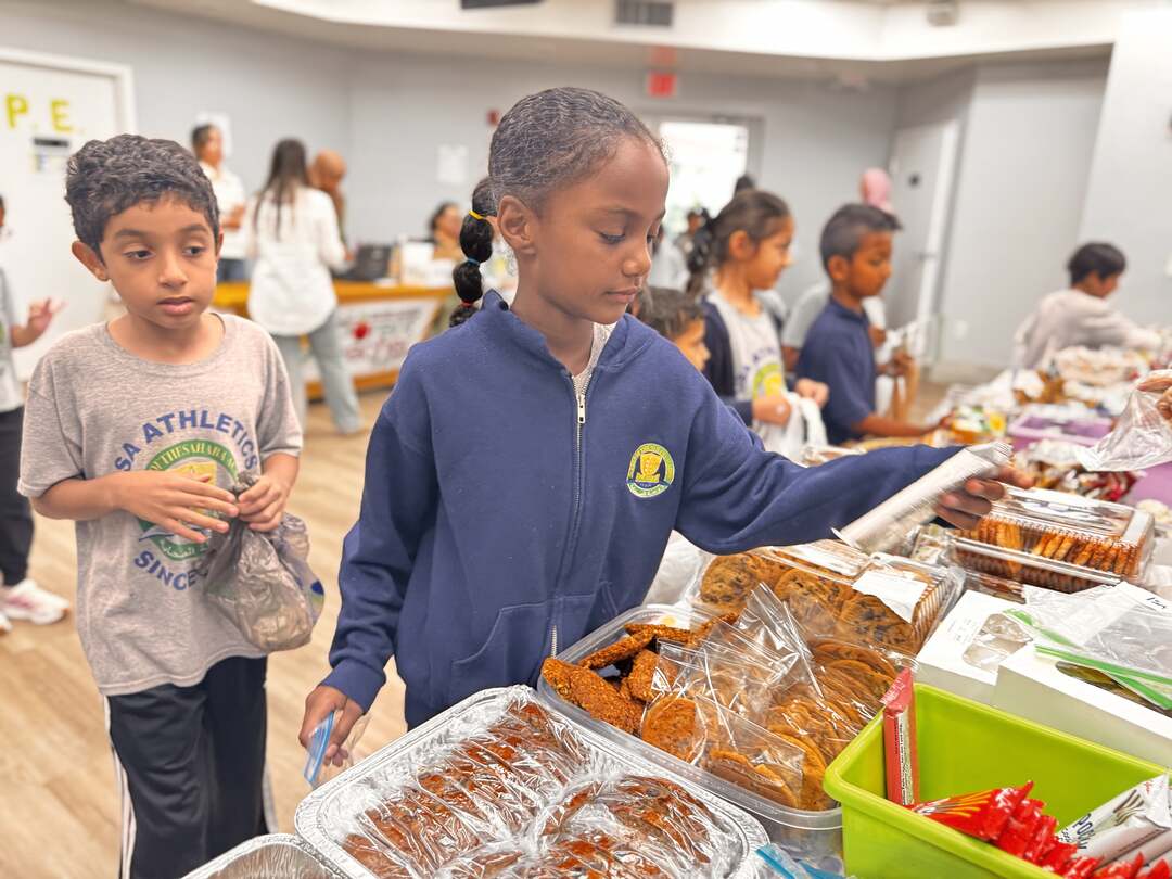 A student reaches for cookies as a classmate waits nearby