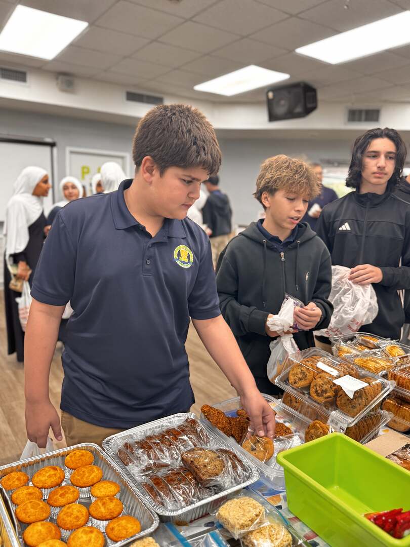 Middle schoolers browse muffins and cookies at the end of the table
