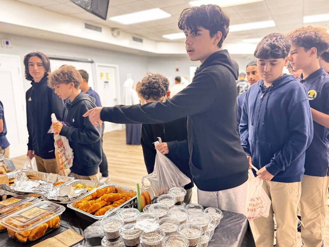 An older student points toward the next treat while friends look on