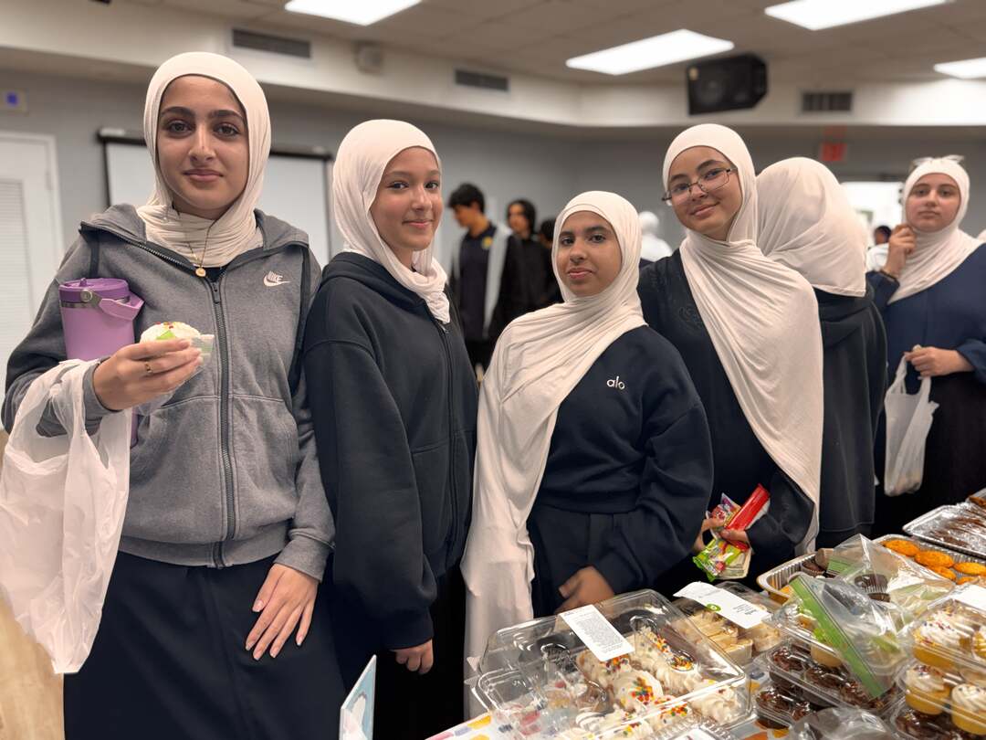 A smiling group of older students lines up with a cupcake and snacks