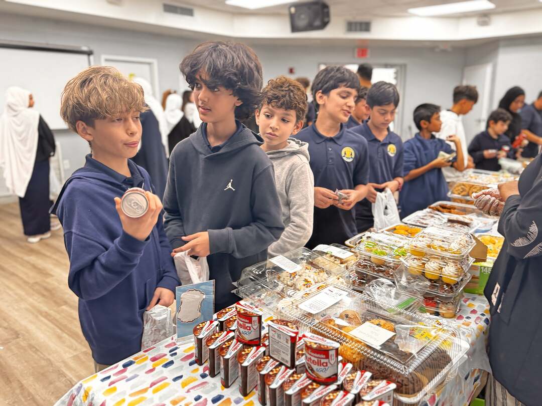 An older student holds up a mini jar while classmates browse