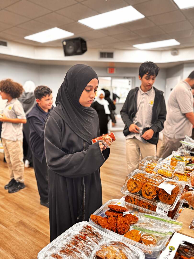An older student checks out a snack beside trays of cookies