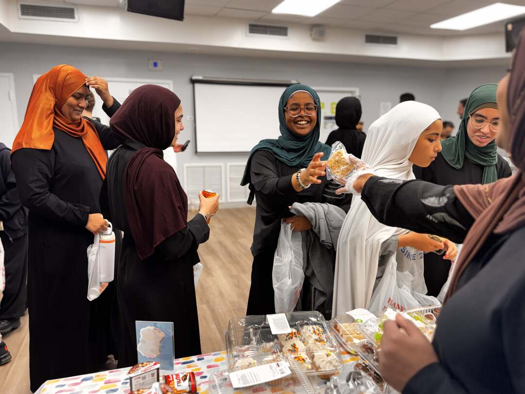 Older students share a laugh as treats are handed across the table