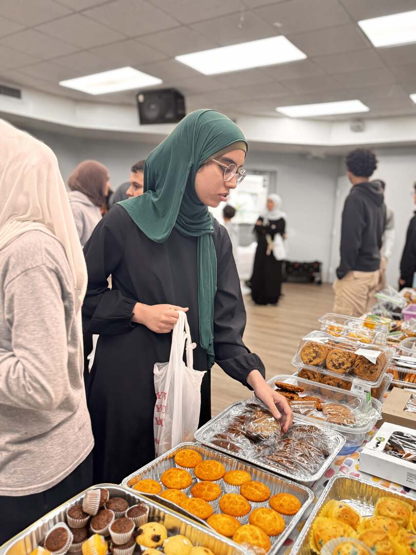 A student reaches for a treat from trays of muffins and brownies
