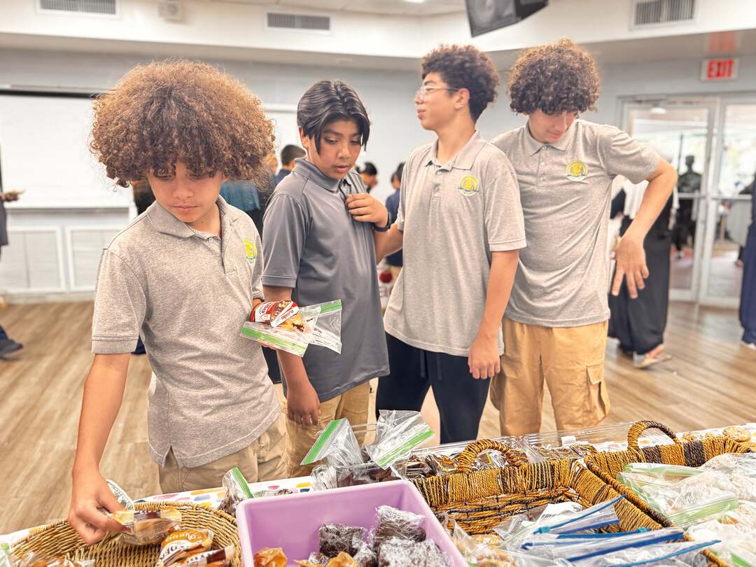 Students in grey polos sort through bags of snacks