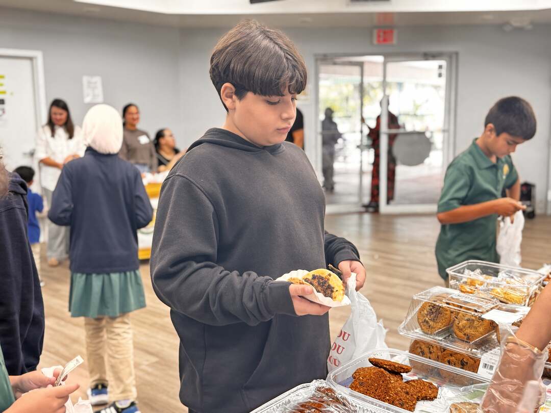 A student carefully carries a fresh cookie on a napkin