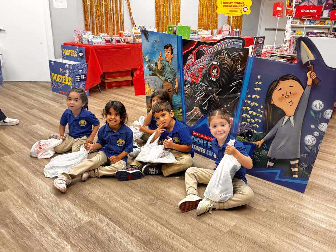 Young students sitting together with their book fair bags