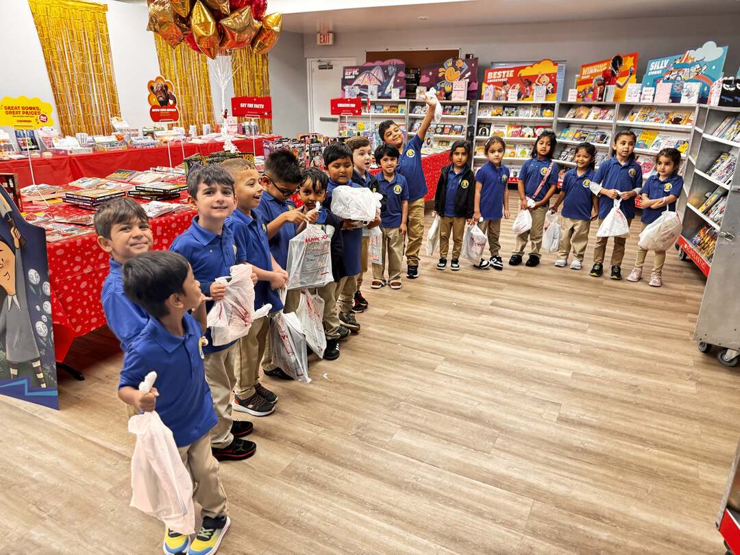 Young students lined up with their book fair bags among the shelves