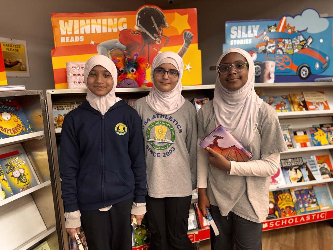 Three students posing among the book displays