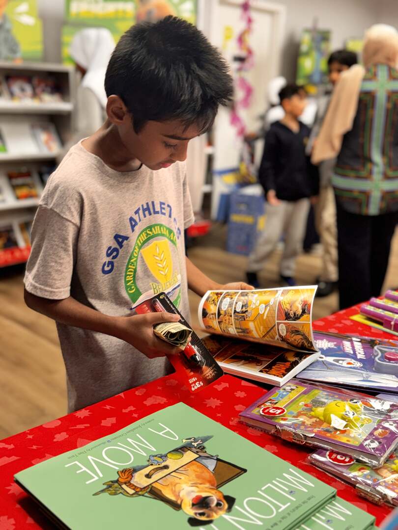 A student flipping through a comic book at the fair table