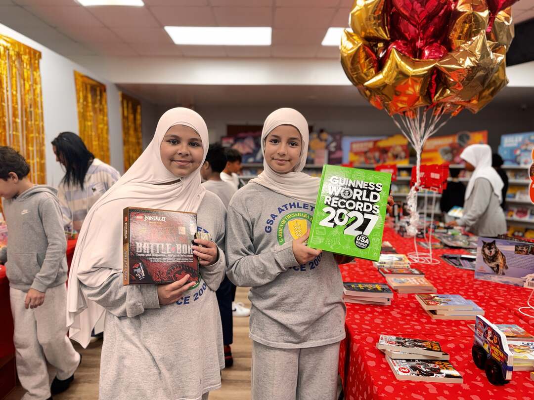Two students holding up a records book and a building book