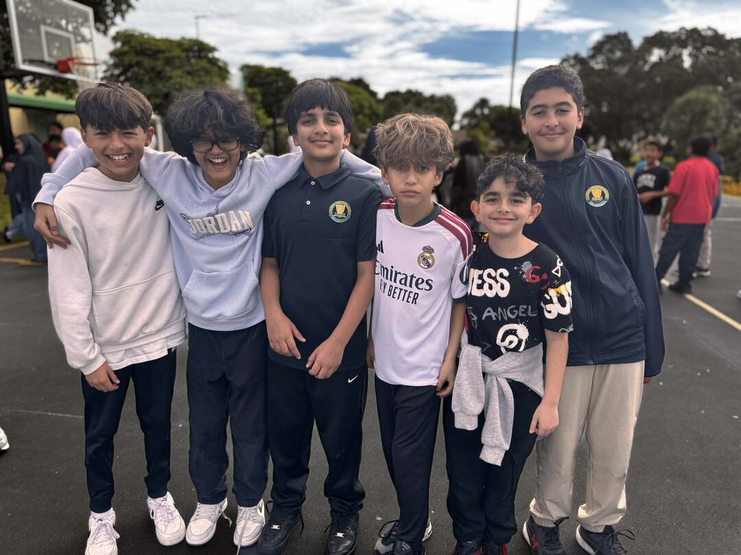 A row of grinning buddies in hoodies and jerseys on the basketball court
